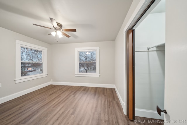 unfurnished bedroom featuring a closet, a ceiling fan, baseboards, and wood finished floors