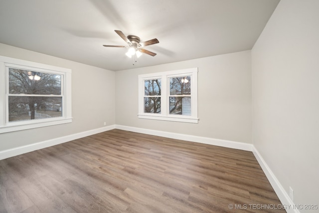 empty room with ceiling fan, baseboards, and wood finished floors