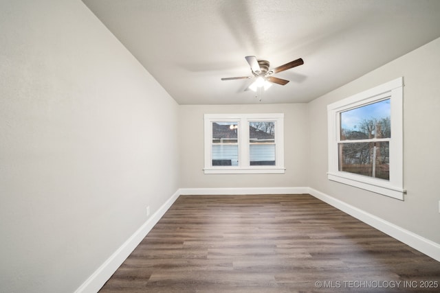 empty room with ceiling fan, baseboards, and dark wood-style floors