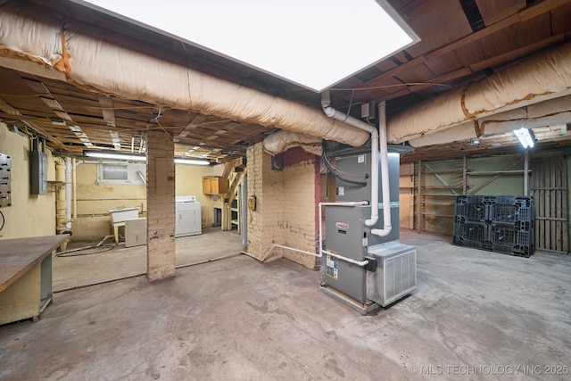 unfinished basement with electric panel, washer / clothes dryer, and heating unit