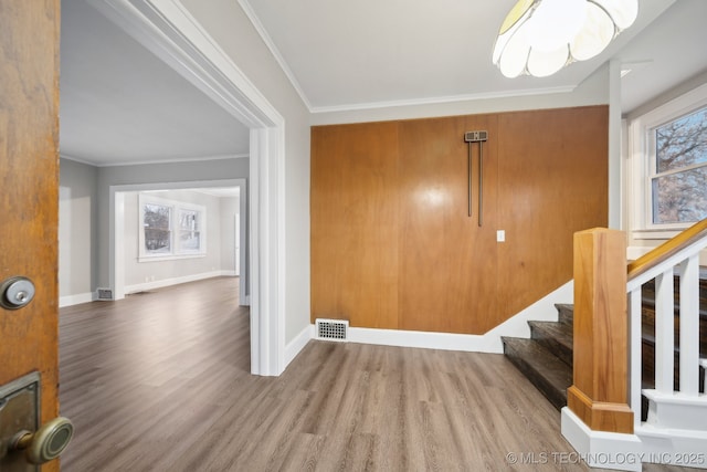 entrance foyer with visible vents, crown molding, baseboards, stairway, and wood finished floors