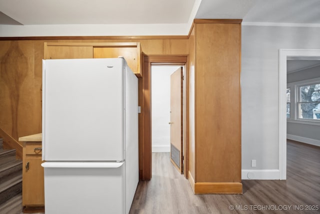 kitchen featuring visible vents, ornamental molding, wood finished floors, freestanding refrigerator, and baseboards