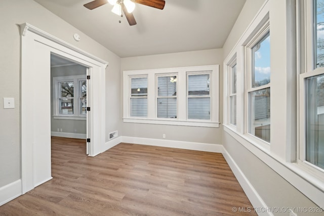 spare room featuring a ceiling fan, wood finished floors, visible vents, and baseboards