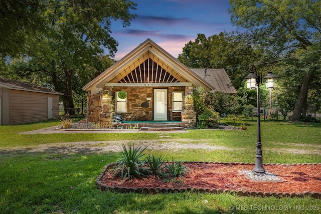 view of front facade with stone siding, a lawn, and an outdoor structure