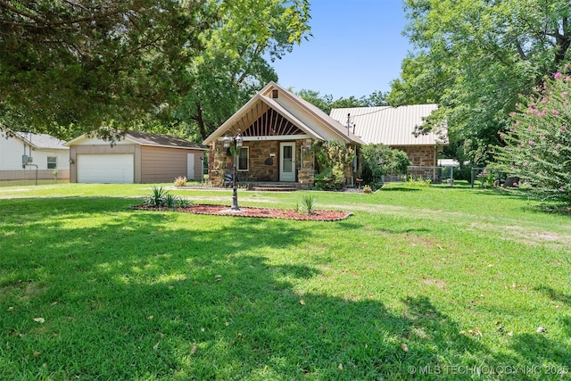 view of front of house with stone siding, an outbuilding, a detached garage, and a front yard