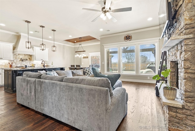 living room featuring a stone fireplace, dark wood finished floors, and ornamental molding