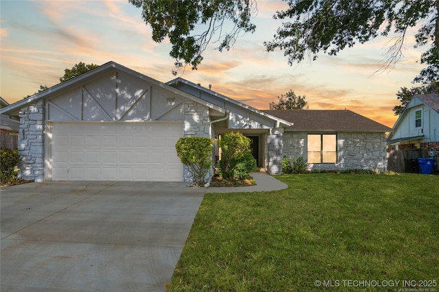 view of front of home with a garage, stone siding, a yard, and concrete driveway