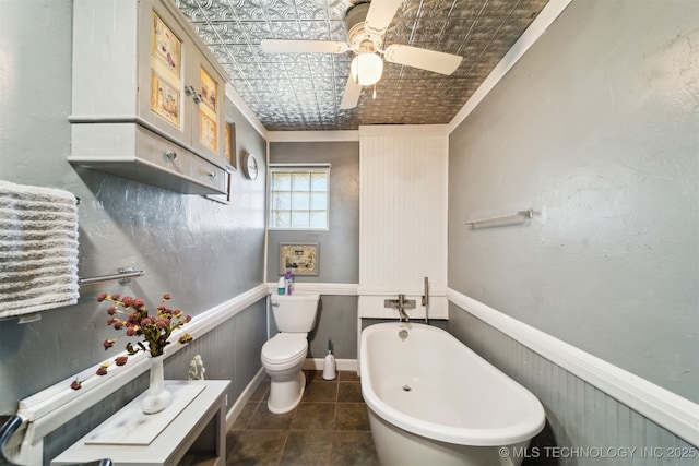 bathroom with a freestanding tub, a wainscoted wall, an ornate ceiling, and toilet