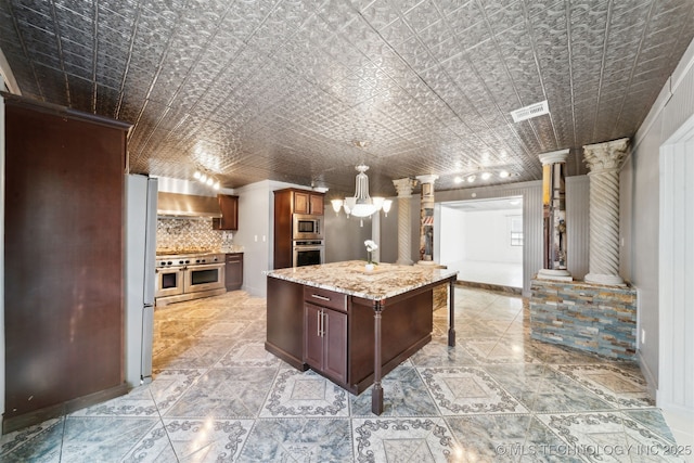 kitchen with wall chimney range hood, decorative columns, decorative backsplash, an ornate ceiling, and stainless steel appliances