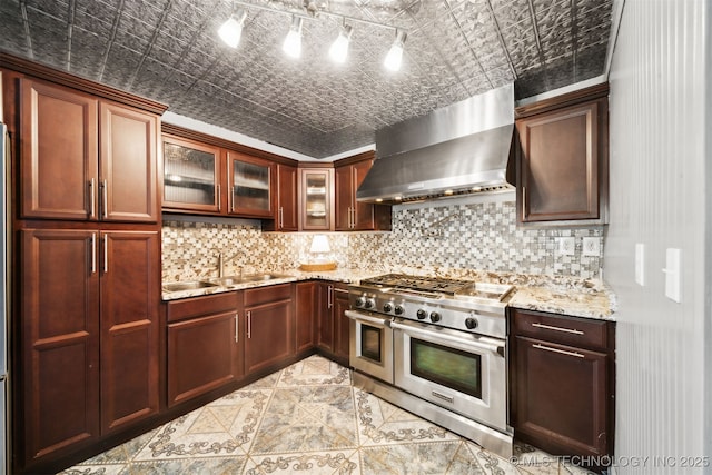 kitchen featuring a sink, double oven range, an ornate ceiling, tasteful backsplash, and wall chimney exhaust hood