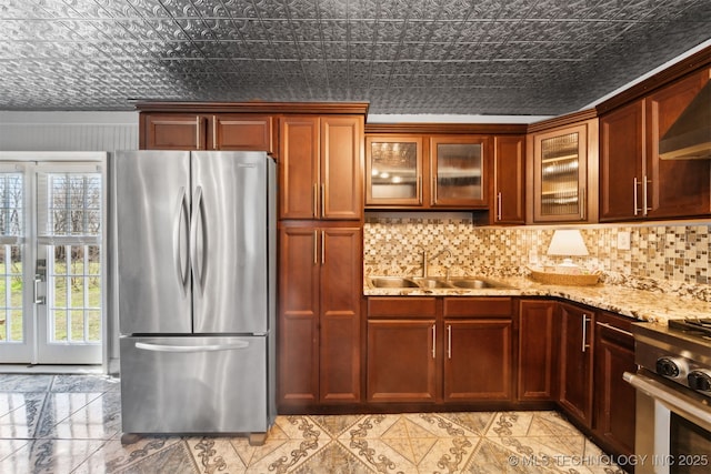 kitchen featuring light stone counters, an ornate ceiling, a sink, stainless steel appliances, and backsplash