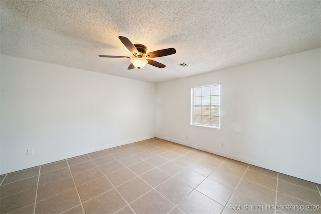 empty room featuring visible vents, a ceiling fan, a textured ceiling, tile patterned flooring, and baseboards