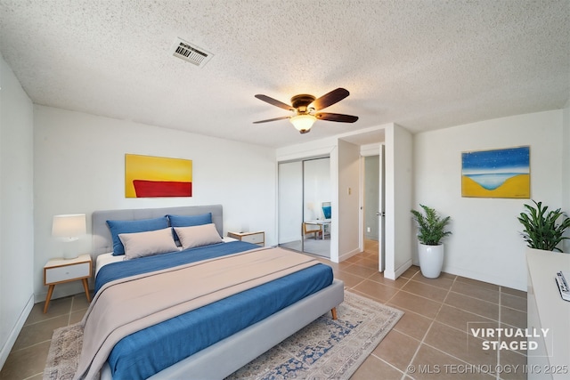 tiled bedroom with visible vents, a textured ceiling, a closet, and ceiling fan