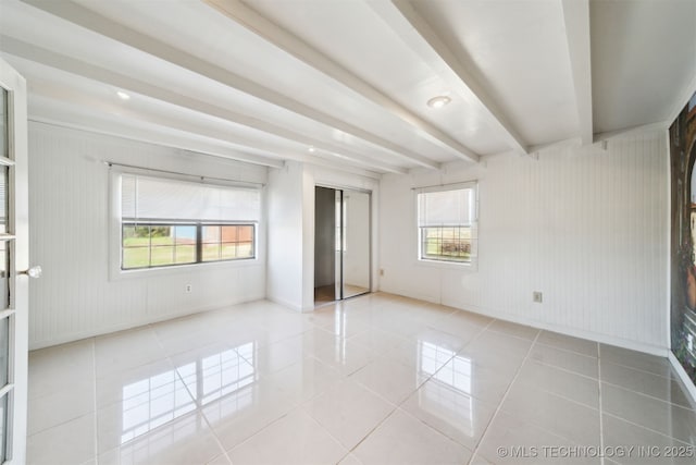 unfurnished bedroom with tile patterned floors, beamed ceiling, baseboards, and a closet