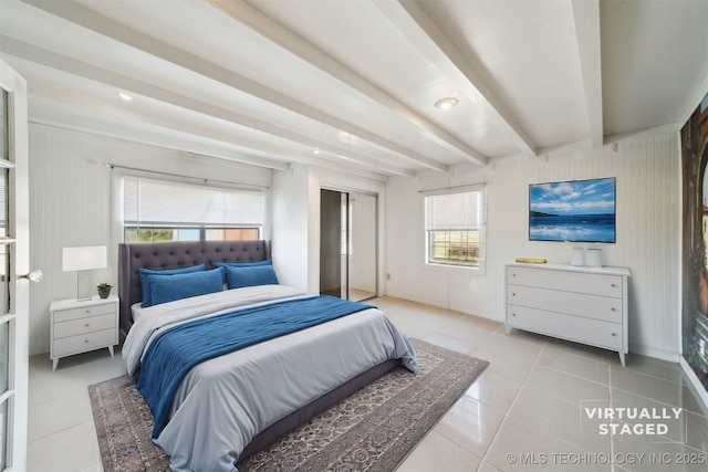 bedroom with light tile patterned floors, beamed ceiling, and a closet