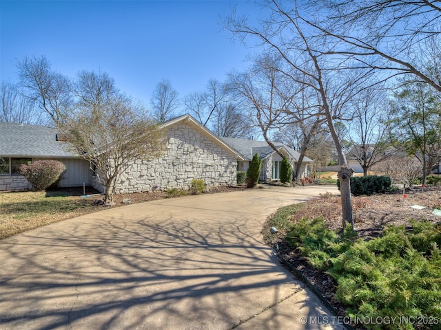 view of property exterior with stone siding and driveway