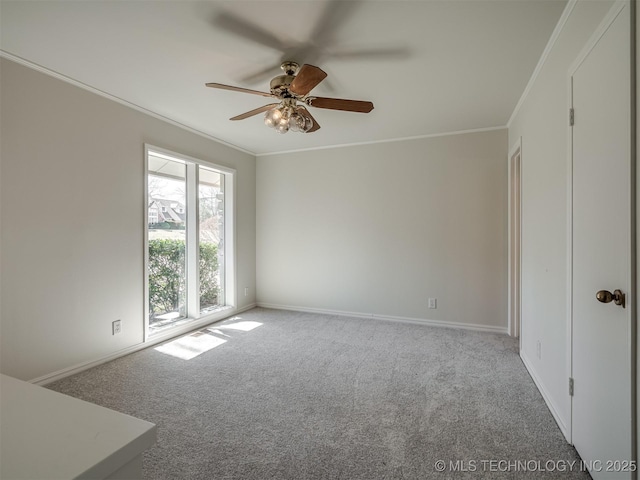 spare room featuring carpet flooring, a ceiling fan, crown molding, and baseboards