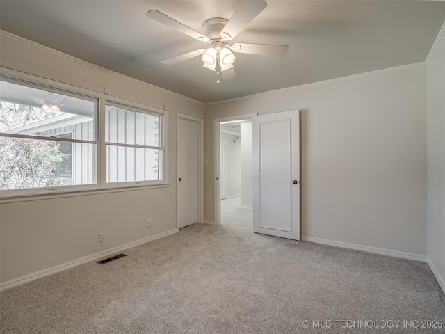 unfurnished bedroom with visible vents, light carpet, a ceiling fan, crown molding, and baseboards