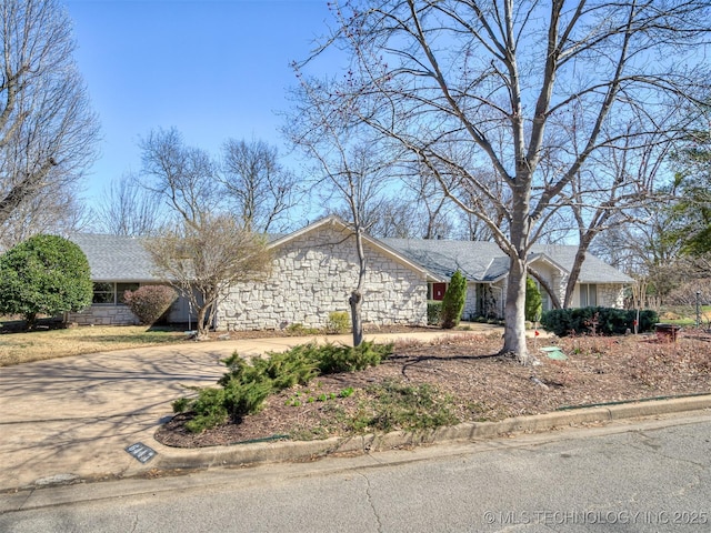 view of front of house featuring stone siding and driveway