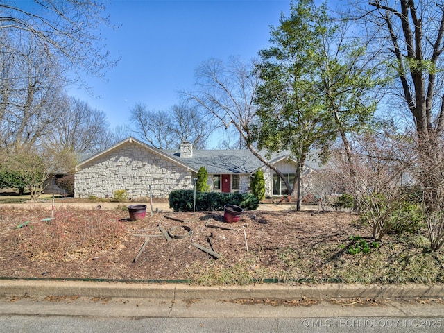 view of front of house with stone siding and a chimney