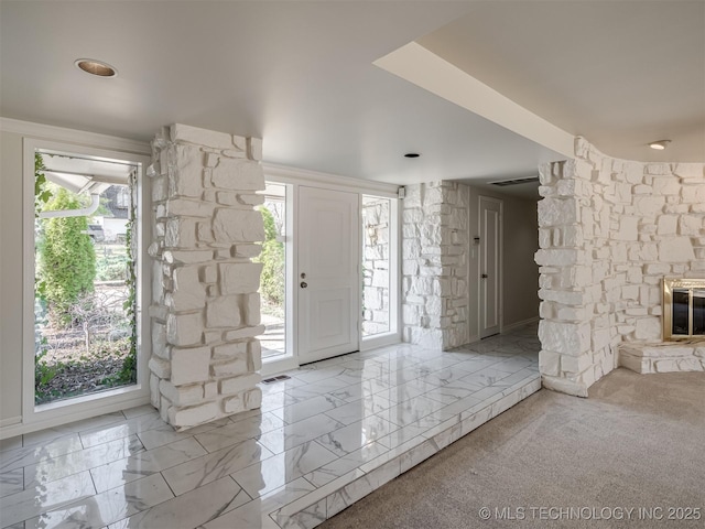 foyer entrance featuring visible vents, marble finish floor, and a fireplace