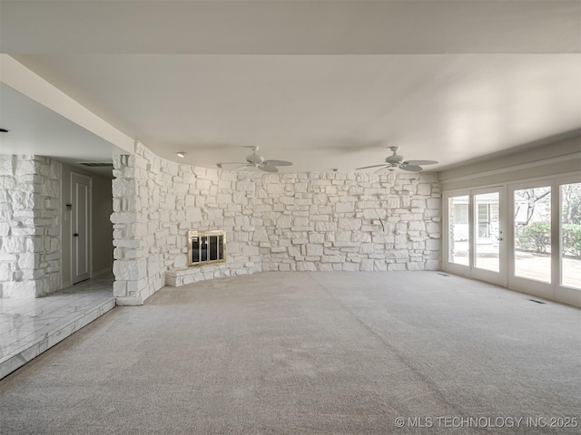 unfurnished living room with visible vents, a fireplace, a ceiling fan, and carpet floors