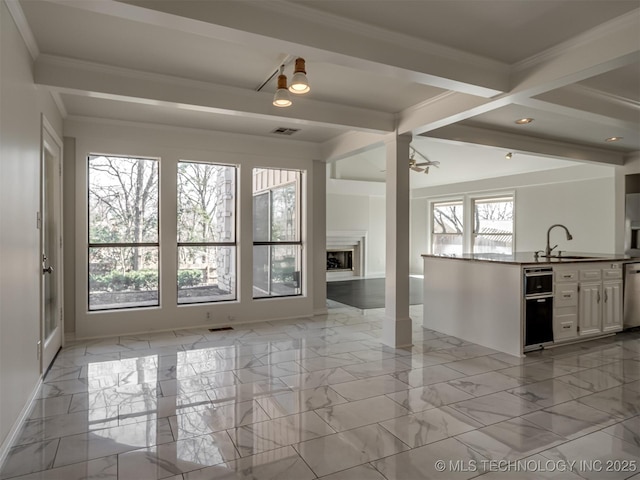 unfurnished living room featuring a sink, beamed ceiling, marble finish floor, and a fireplace