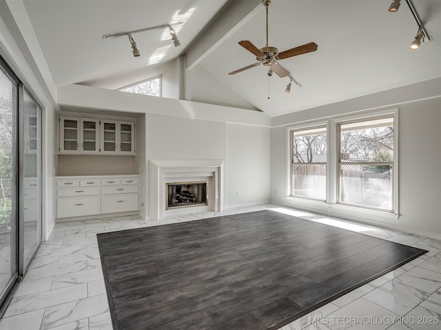 unfurnished living room with track lighting, marble finish floor, and a fireplace