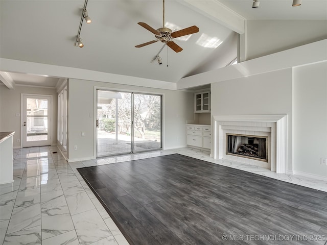 unfurnished living room featuring a ceiling fan, baseboards, beam ceiling, a high end fireplace, and marble finish floor