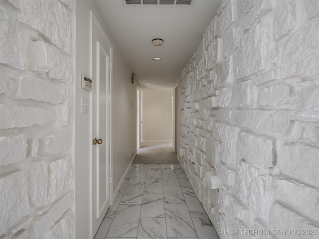 hallway with visible vents, baseboards, and marble finish floor