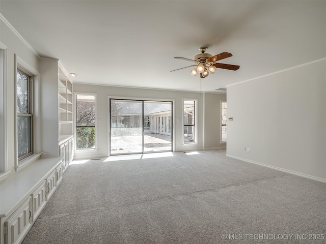 spare room with crown molding, ceiling fan, baseboards, built in features, and carpet floors