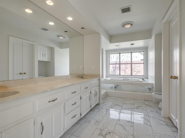 full bathroom featuring visible vents, toilet, double vanity, a bath, and marble finish floor