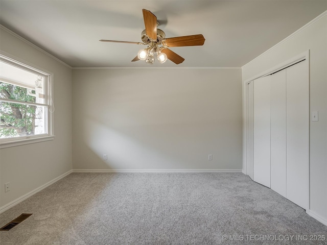 unfurnished bedroom with visible vents, crown molding, ceiling fan, carpet flooring, and a closet