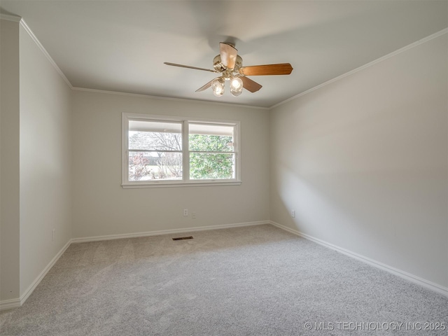 spare room with a ceiling fan, visible vents, carpet floors, and ornamental molding