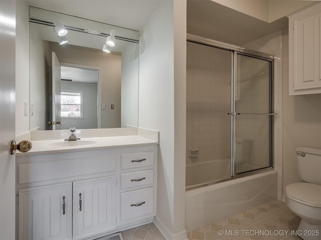 bathroom featuring tile patterned flooring, combined bath / shower with glass door, toilet, and vanity