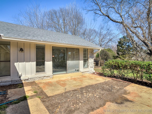 entrance to property with a patio area, board and batten siding, and a shingled roof