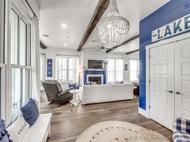 living room featuring visible vents, beamed ceiling, a large fireplace, and wood finished floors