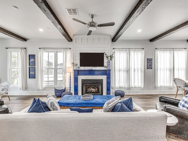 living room with visible vents, baseboards, wood finished floors, and a fireplace