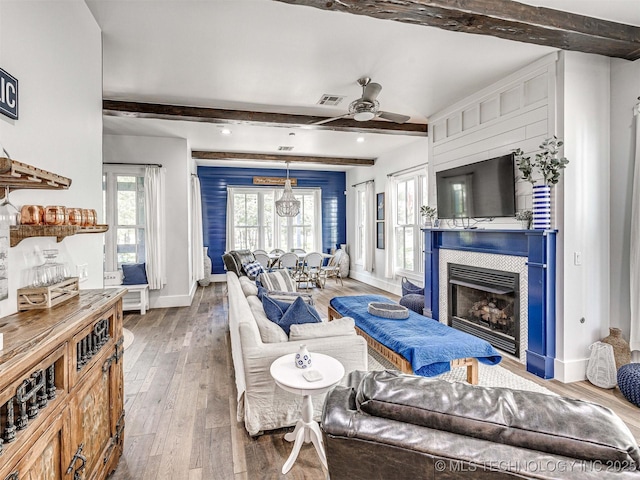 living area featuring hardwood / wood-style flooring, beamed ceiling, a fireplace, and baseboards