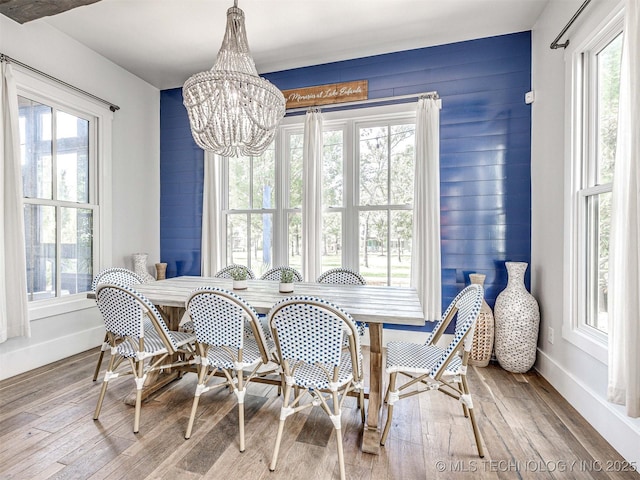 dining space featuring baseboards, plenty of natural light, a chandelier, and hardwood / wood-style flooring