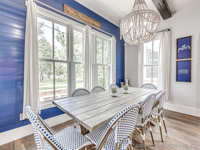 dining space with beam ceiling, a notable chandelier, baseboards, and wood finished floors