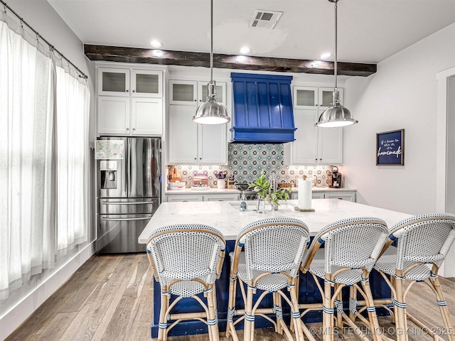 kitchen featuring visible vents, decorative backsplash, light wood-style flooring, white cabinets, and stainless steel fridge