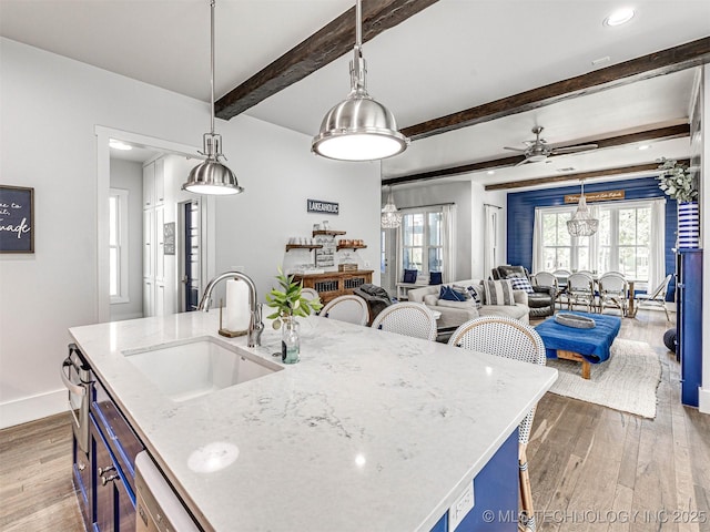 kitchen featuring hardwood / wood-style flooring, light stone countertops, and a sink