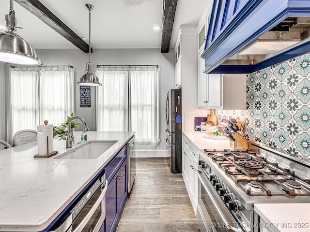 kitchen with ventilation hood, beam ceiling, decorative backsplash, appliances with stainless steel finishes, and a sink