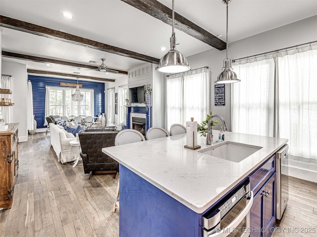 kitchen with a sink, light stone countertops, open floor plan, a fireplace, and wood-type flooring