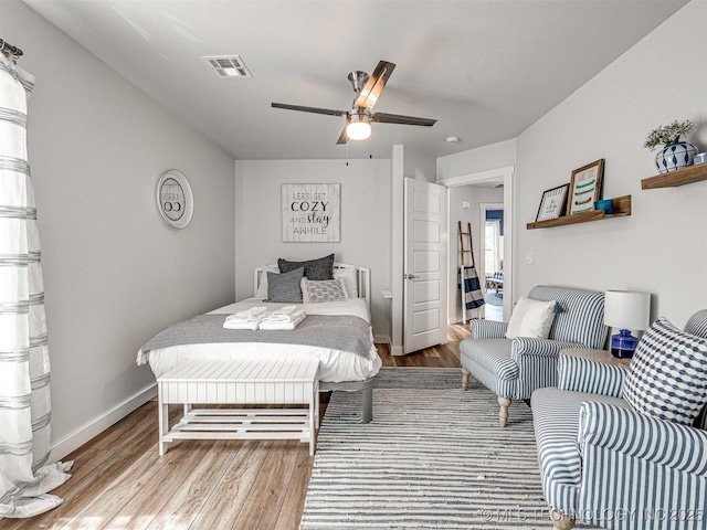 bedroom featuring visible vents, a ceiling fan, baseboards, and wood finished floors