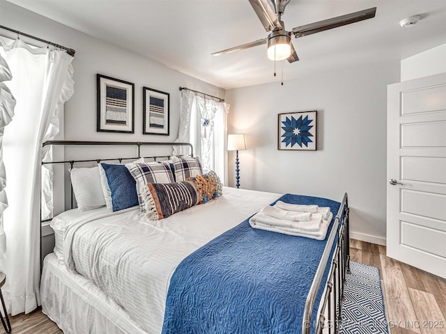 bedroom featuring ceiling fan, baseboards, and wood finished floors