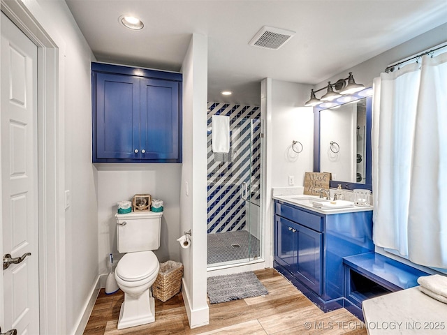 bathroom featuring visible vents, toilet, a stall shower, wood finished floors, and vanity