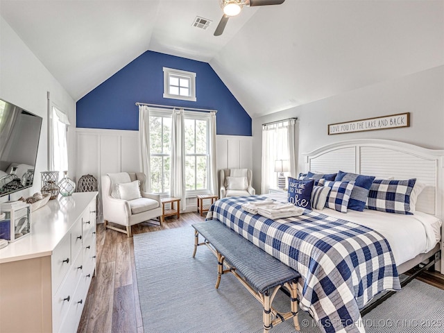 bedroom with visible vents, lofted ceiling, wood finished floors, and a wainscoted wall