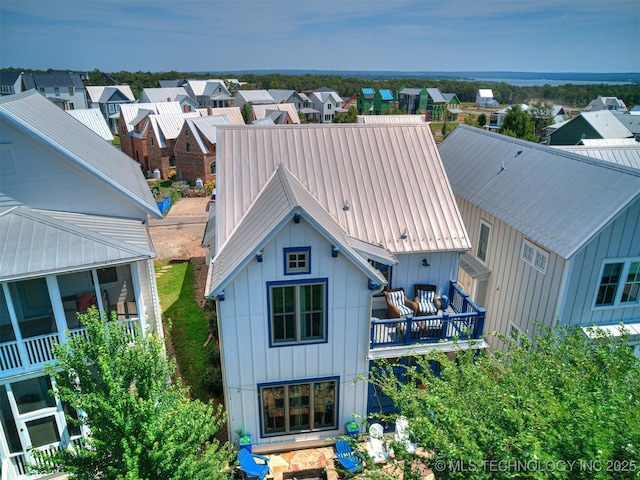 rear view of property with board and batten siding, a residential view, and metal roof